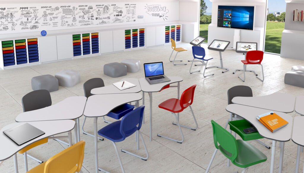 Un aula luminosa y moderna con sillas de colores y Mobiliario Escolar como pupitres blancos, ordenadores portátiles y tabletas. En una de las paredes hay armarios con cubos de colores, grandes pantallas digitales en la parte delantera y ventanas con vistas al césped y los árboles.